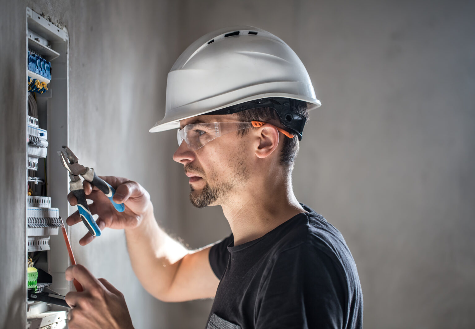 Man, an electrical technician working in a switchboard with fuses